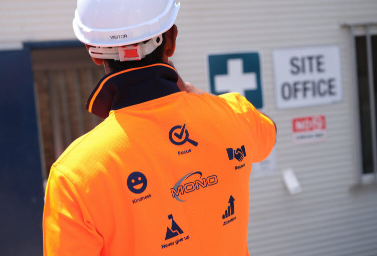 Worker wearing orange uniform with icons at the back