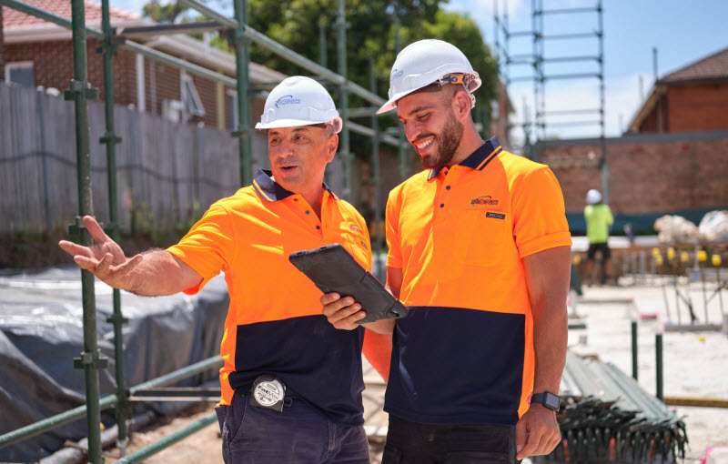 Workers wearing uniform in construction site checking a tablet